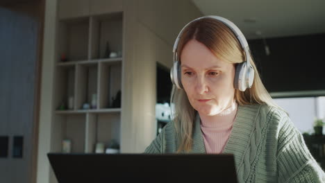 a woman in headphones uses a laptop. work from home concept