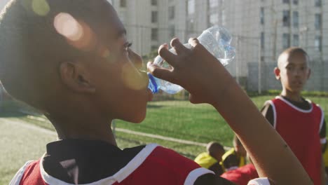 des enfants de football buvant de l'eau par une journée ensoleillée.