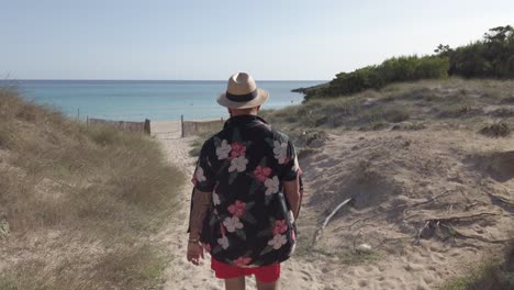 man walking through the dunes of cala agulla