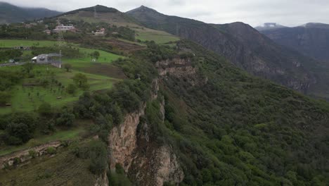 Cliff-side-aerial-follows-sky-tram-cable-car-approaching-top-station