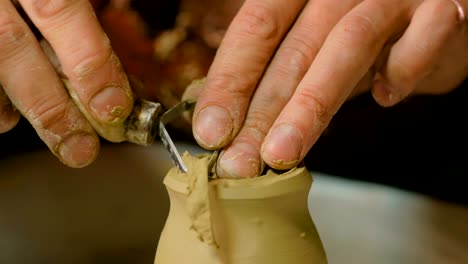 professional potter shaping mug with special tool in pottery workshop