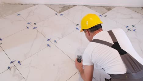 a craftsman in overalls installs tiles on the floor repairs inside the house construction