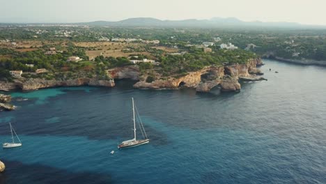 vista asombrosa de la costa este de mallorca, españa - es pontas cala santanyi - formación rocosa de acantilados - yate de vela en aguas turquesas mientras sale el sol