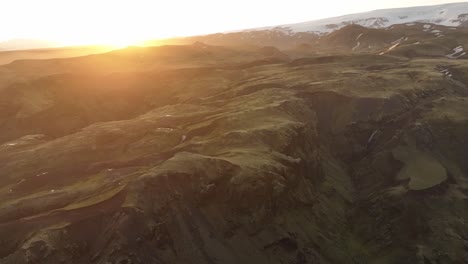aerial view of the golden sunrise illuminating volcanic highlands in northern iceland, casting warm light over the rugged, untouched landscape.