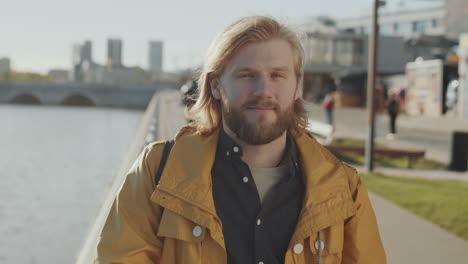 portrait of young man on river embankment in city
