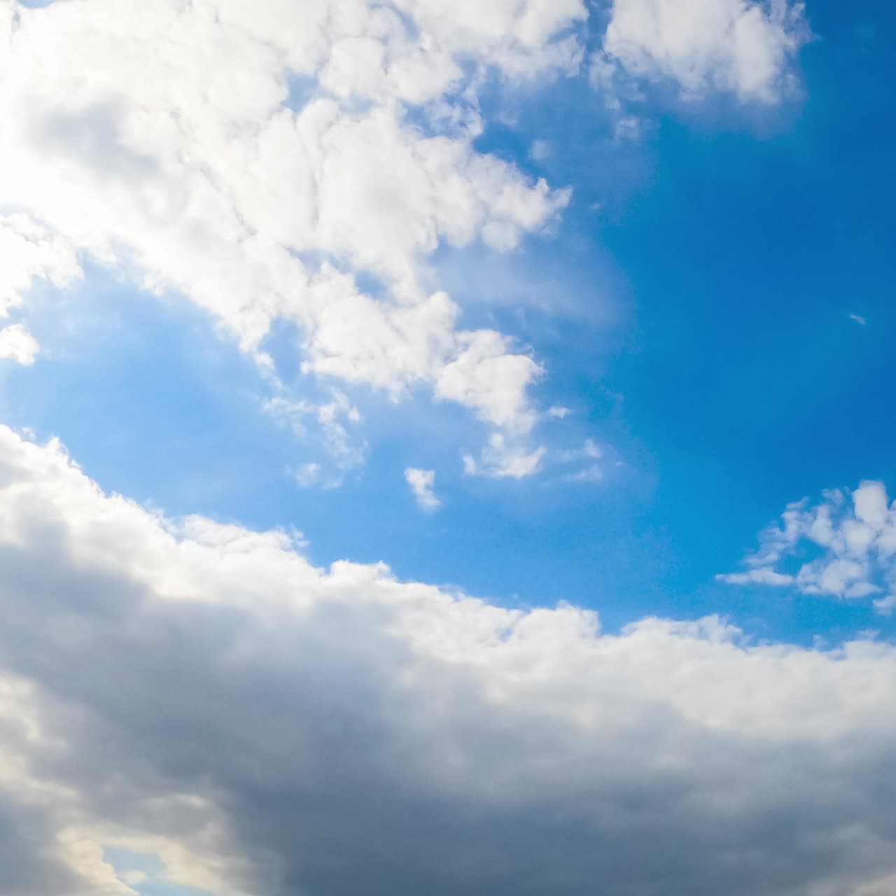 Huge white soft cloud lit by the bright sun changes its shape in the wind. Cloudy sky in summer. View from below. Timelapse