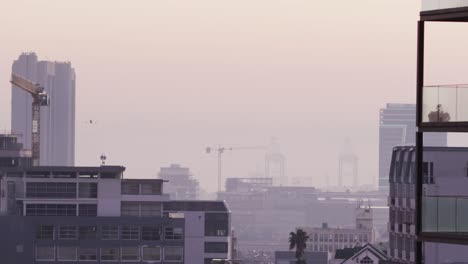 vista general del paisaje urbano con múltiples edificios, el sitio de construcción y el astillero cubiertos de niebla