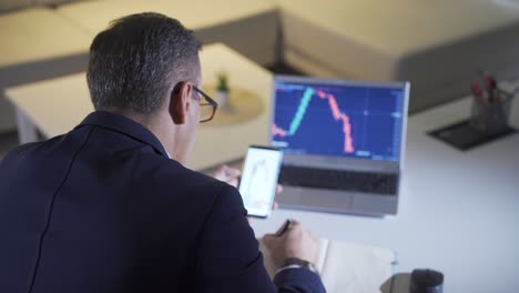 man analyzing stock market and cryptocurrency charts from laptop.