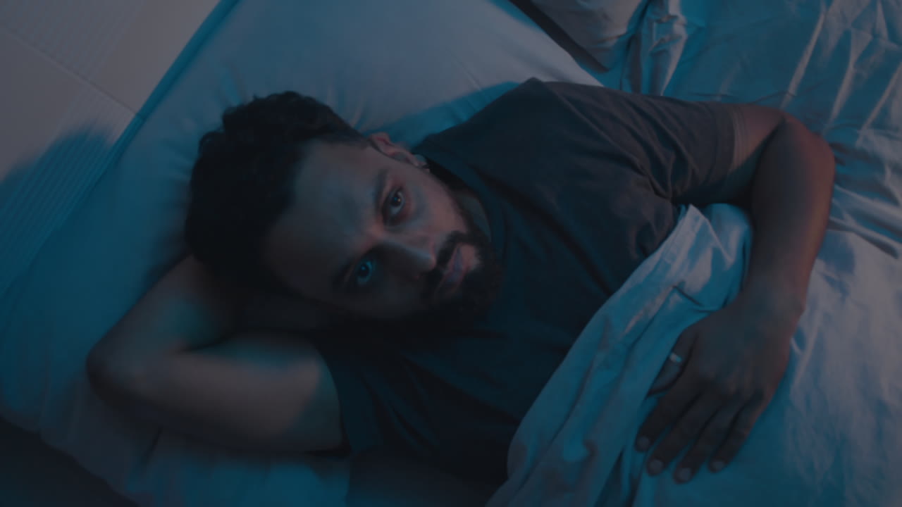 hombre con insomnio acostado en la cama por la noche