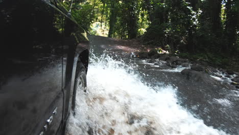 action shot of car driving through water on road in jungle, hawaii