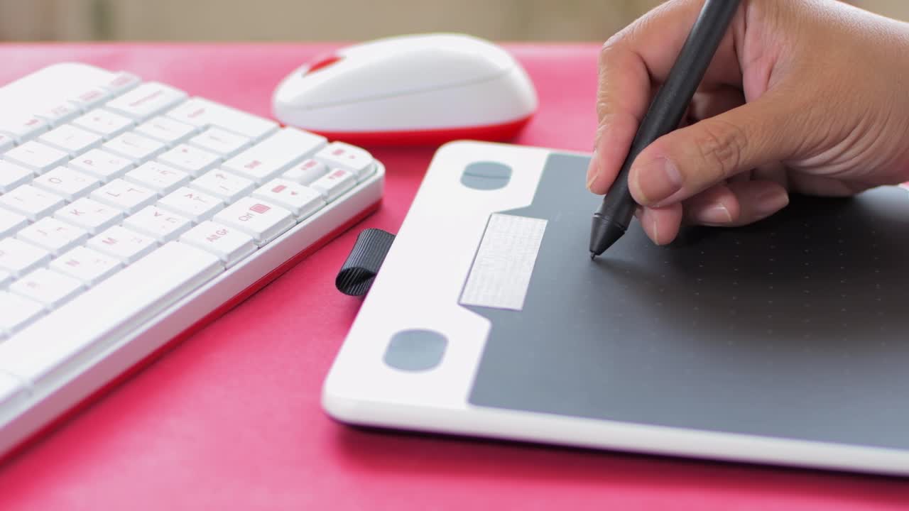Woman's hand using mouse and graphic tablet to design. On red table.