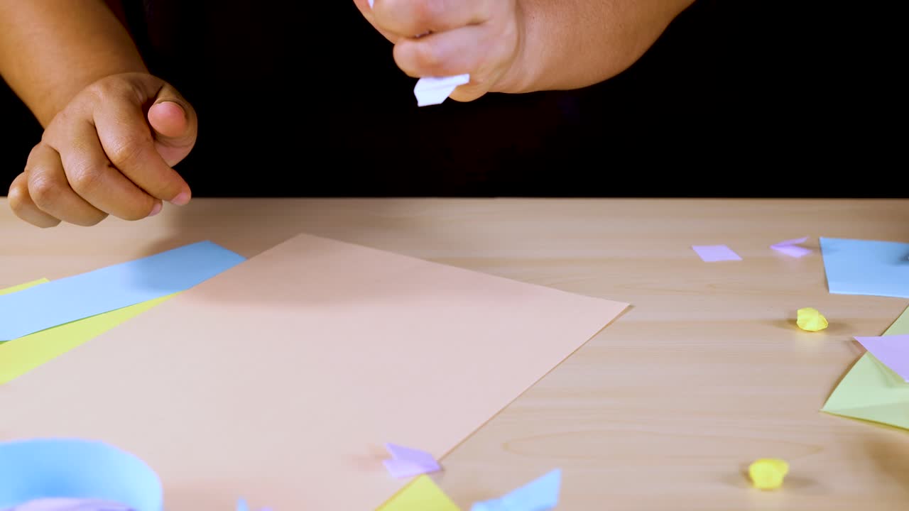 Person crumples white paper by hand on pastel craft table under bright, even lighting