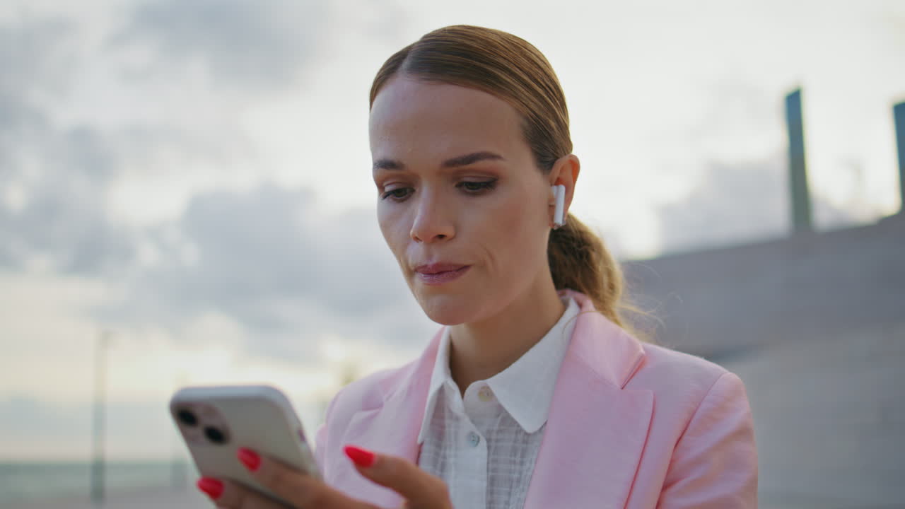 Donna preoccupata che usa il cellulare con le cuffie all'aperto, primo piano. CEO nervosa.