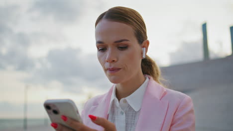 mujer preocupada trabajando teléfono celular en auriculares al aire libre de cerca. ceo nervioso