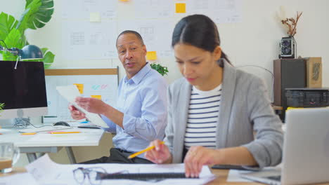 male and female architects working in office at desks on plans for new building