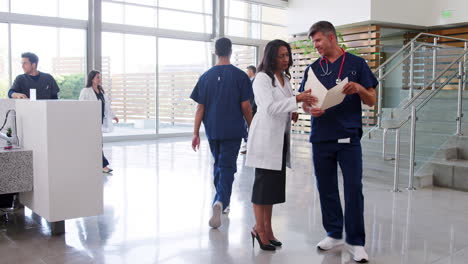 male and female doctors talking in a hospital lobby