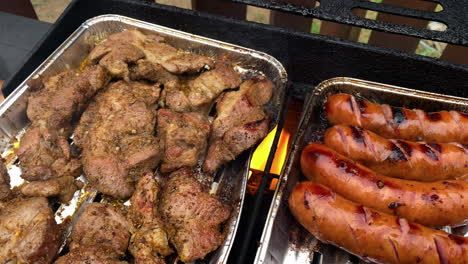 asar carne de cerdo marinada y salchichas en una parrilla sobre el fuego - primer plano, tiro en ángulo alto