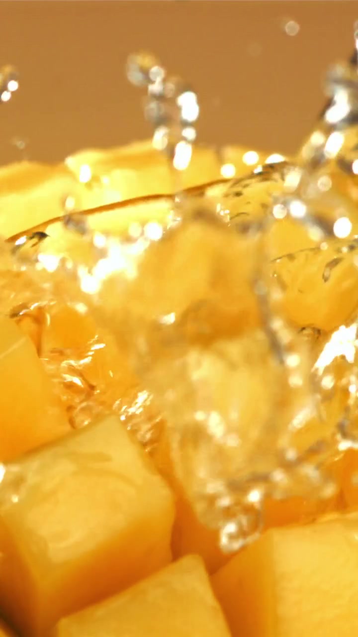 Acqua rinfrescante che schizza su cubetti di mango giallo vivace