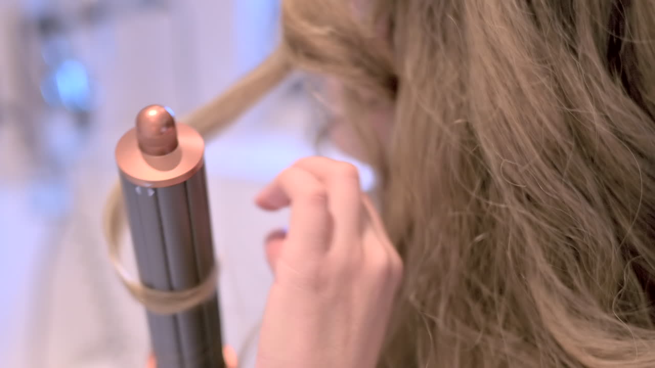 Close up of a blonde woman using a hair curler