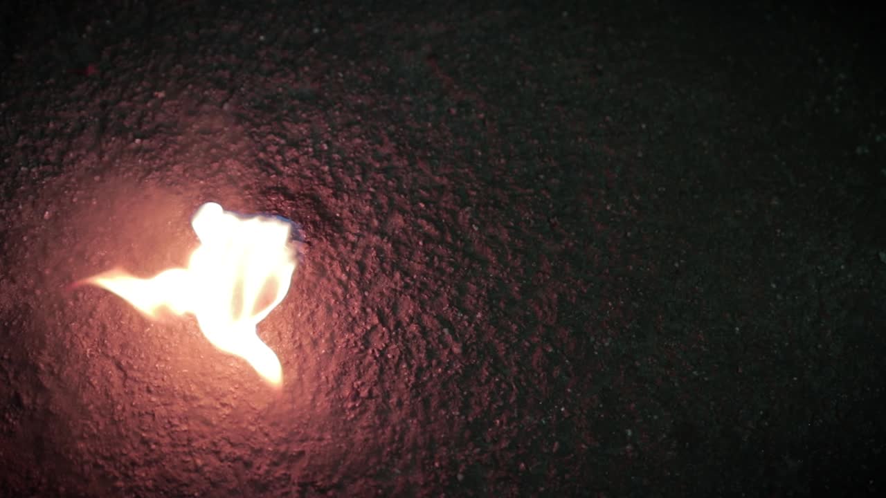 A cup of coal burning on the ground. Handheld, top view