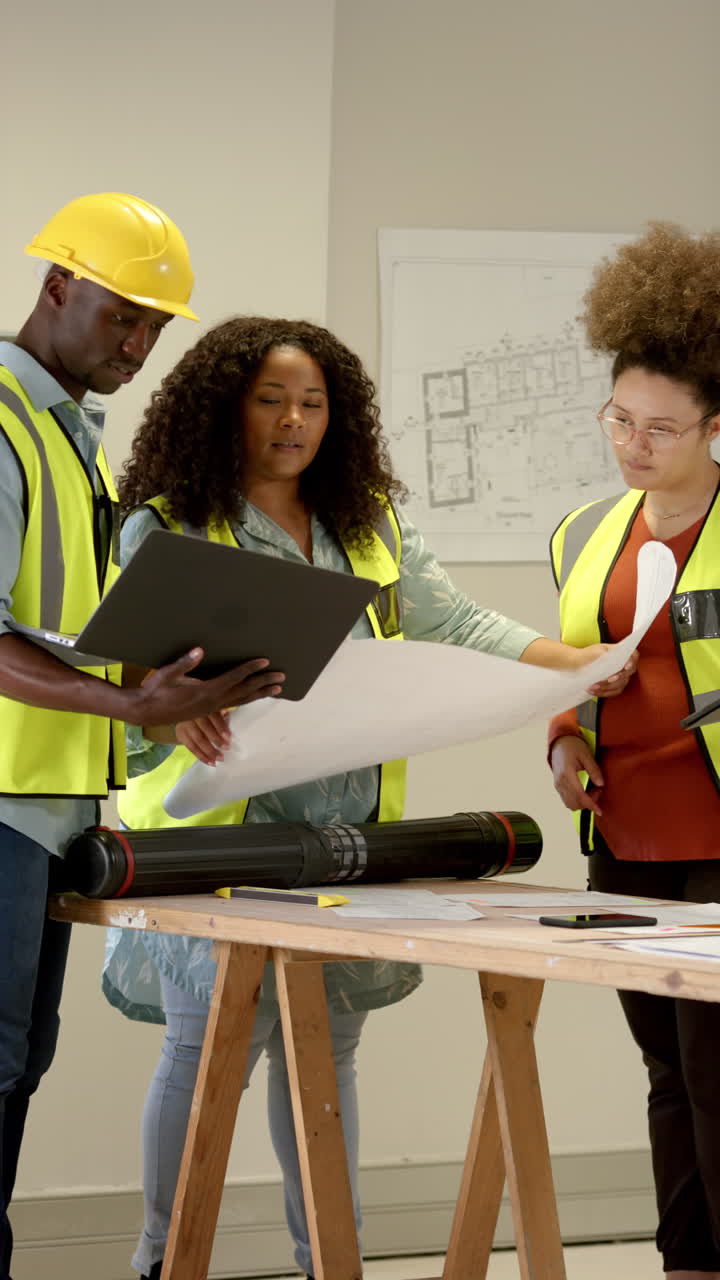 Vertical video of casual diverse architects looking at plans, slow motion, copy space