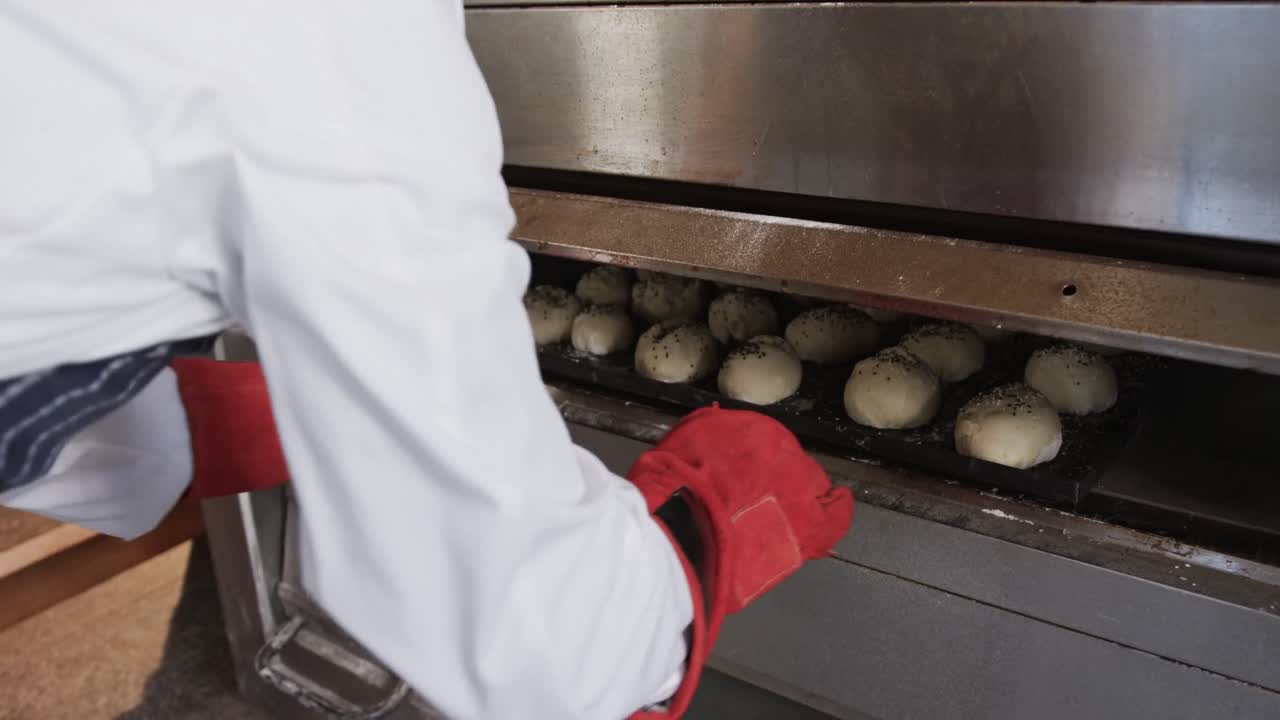 афроамериканский мужчина-пекарь, работающий на кухне пекарни, помещая роллы в духовку в замедленном движении