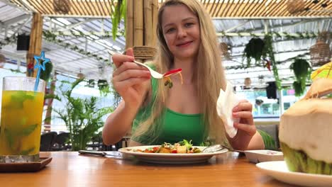 mujer comiendo ensalada en un restaurante tropical