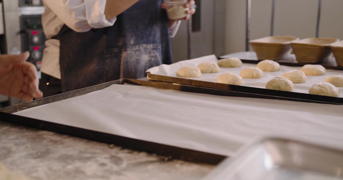 As brush touches, rounds are being glazed divided shaped dusted and staged for proofing at counter