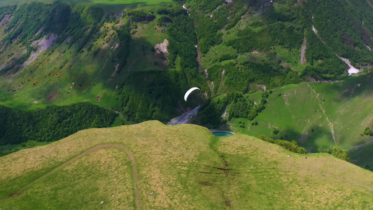 tiro de dron en ángulo descendente siguiendo un parapente en gudauri georgia