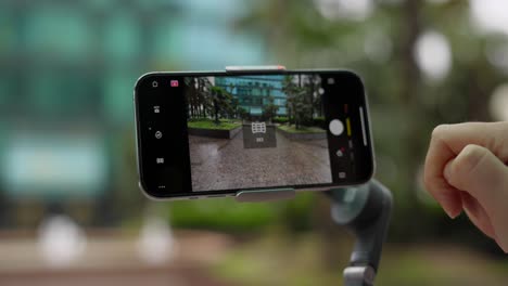 Close-up-shot-of-finger-changing-camera-settings-on-phone-mounted-on-gimbal