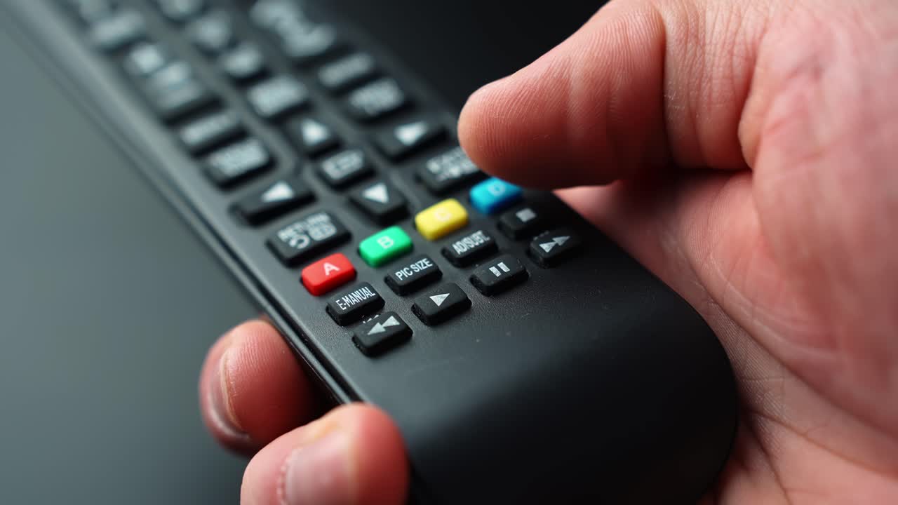 Close-up of a hand pressing the rewind button on a TV remote control, skipping back during video playback with shallow depth of field for streaming and home entertainment b-roll
