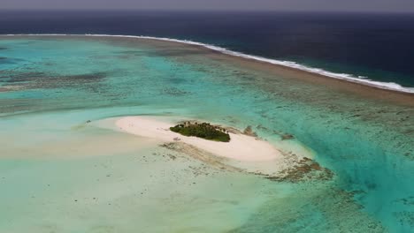 high aerial orbit with pan down over small sandy island covered in palm trees