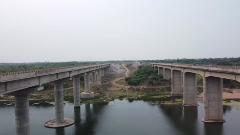 highway bridge built over the river basin in the indian rural terrain, aerial view