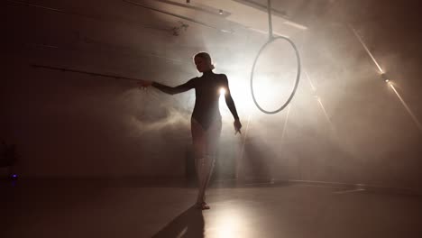 young female artist practicing with the aerial loop in a smoky room. low angle