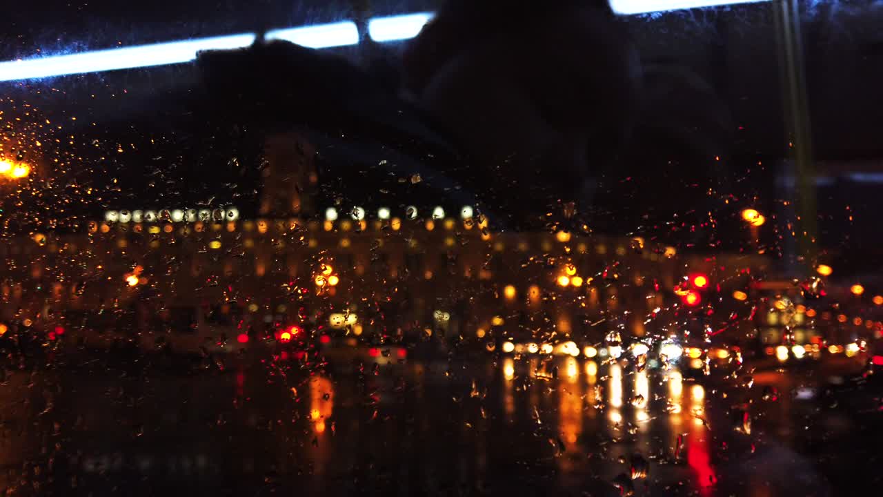 비가 내리는 동안 밤의 도시 거리에서 초점을 맞추지 않은 불빛