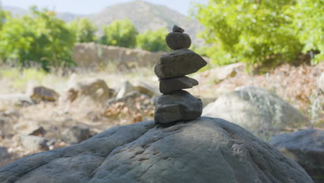 panning shot of cairn with greenery and mountains in the background located in santa paula punch bowls southern california