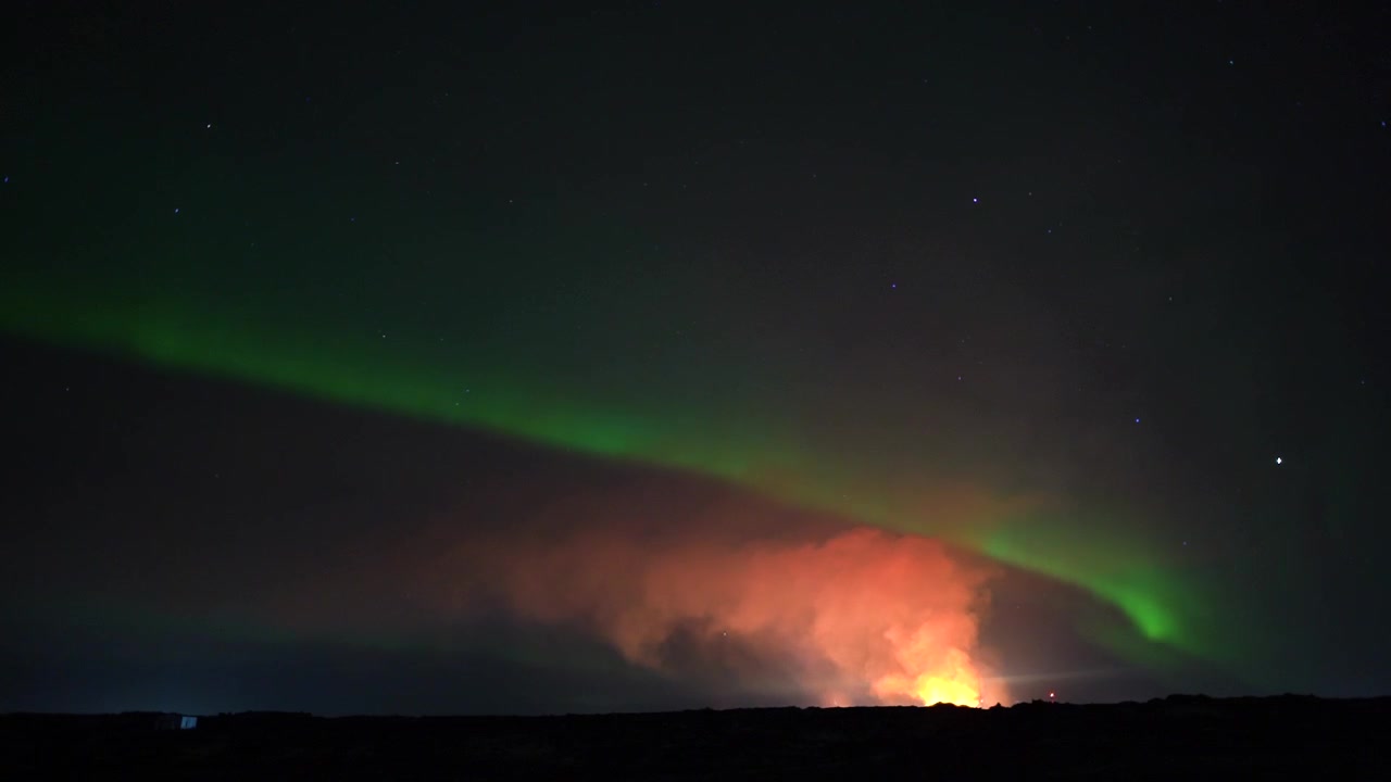 Esplosione vulcanica e aurore boreali verdi nel cielo notturno dell'Islanda. Ampia ripresa in time-lapse.