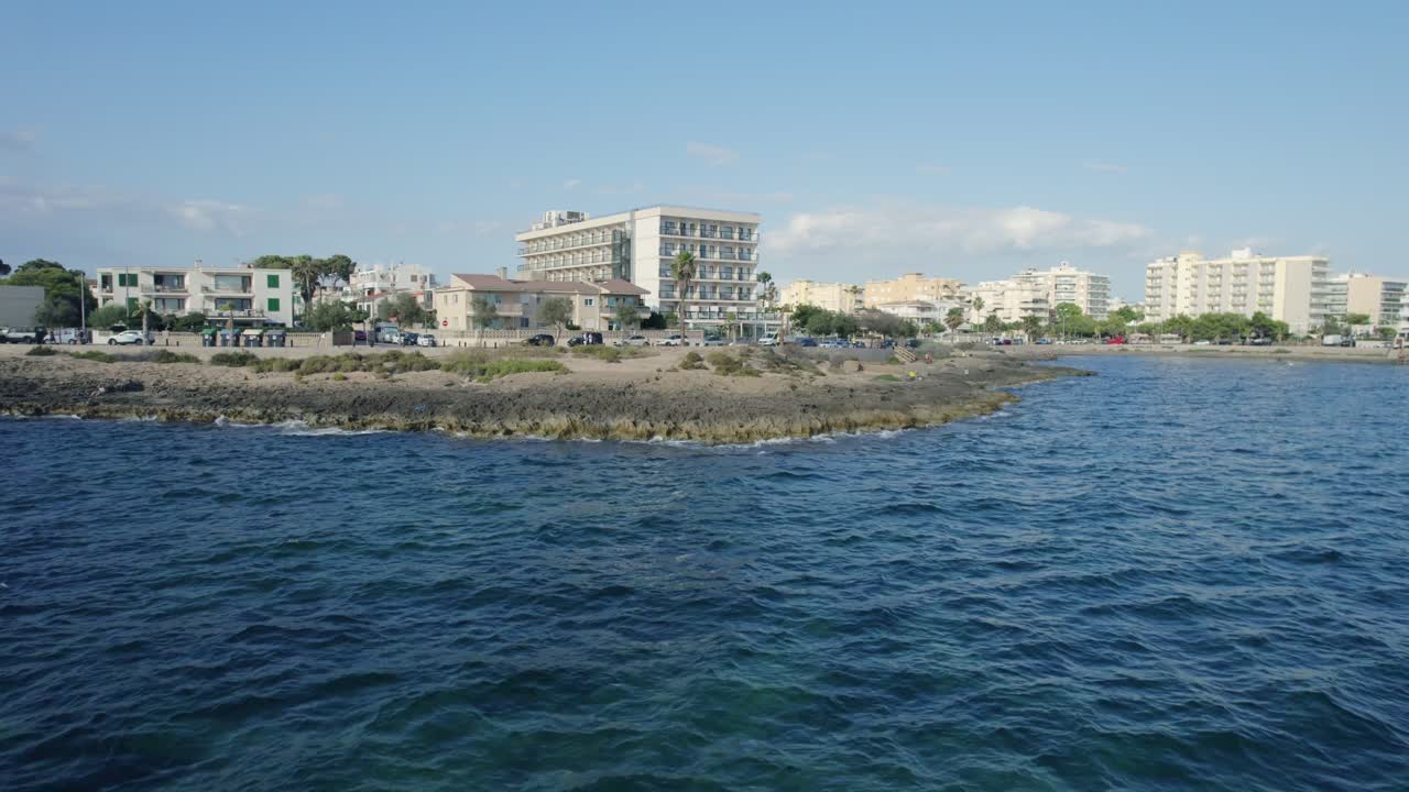 마요르카의 아름다움은 이 매혹적인 드론 영상으로 바다 바닥에서 시작하여 섬의 경치적인 풍경을 드러내기 위해 상승합니다. 건물, 도로, 나무 및 자동차를 포함한 도시 풍경.