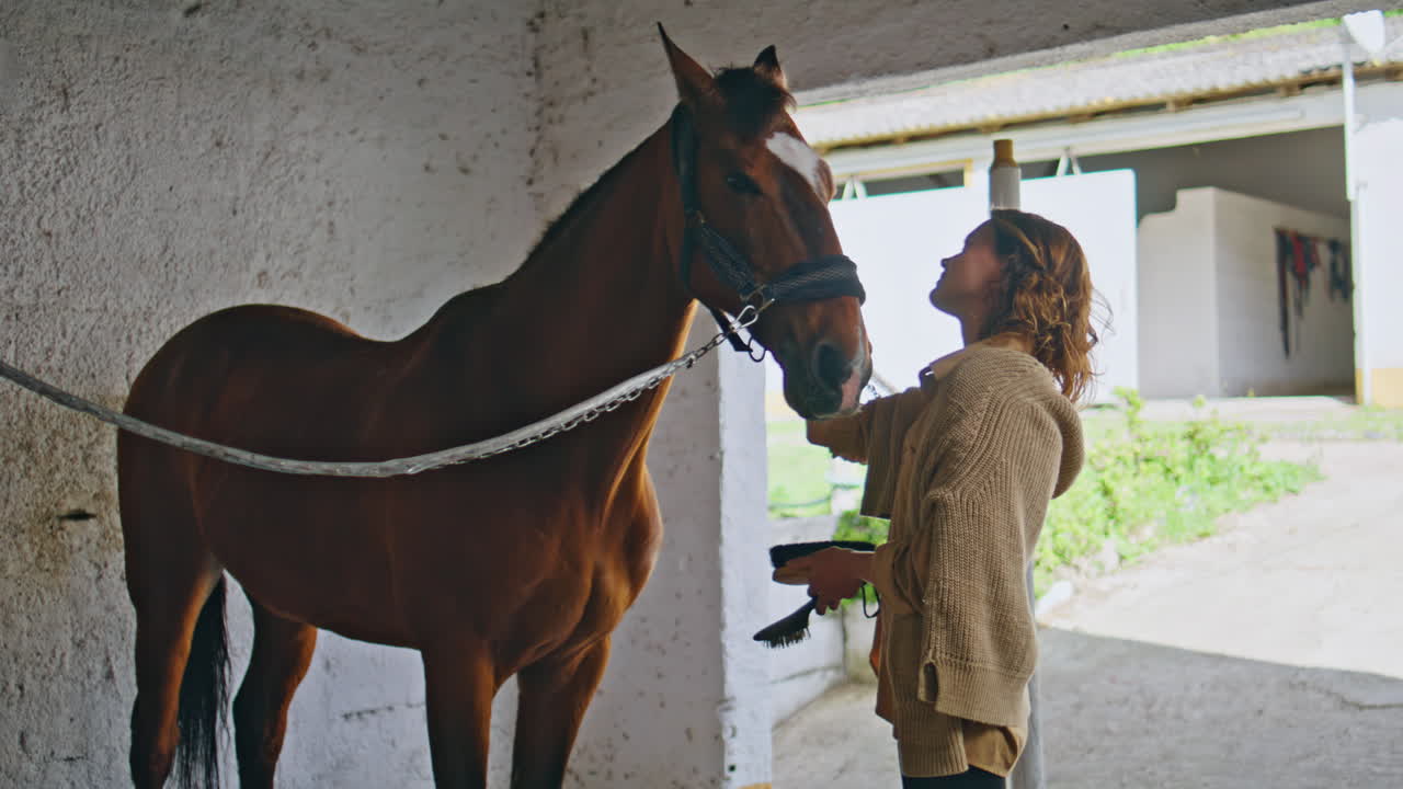 Affectionate cowgirl petting horse in barn closeup. Lady with animal at ranch