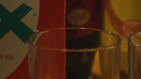 pan across two drinking glasses and cereal box, close up in dark room
