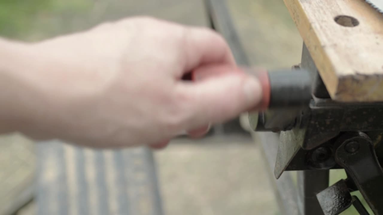 나무 작업대의 손잡이를 수동으로 돌리는 노동자의 손