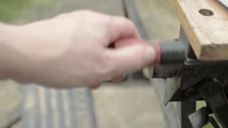 workman hand manually turning the handle of a wooden workbench