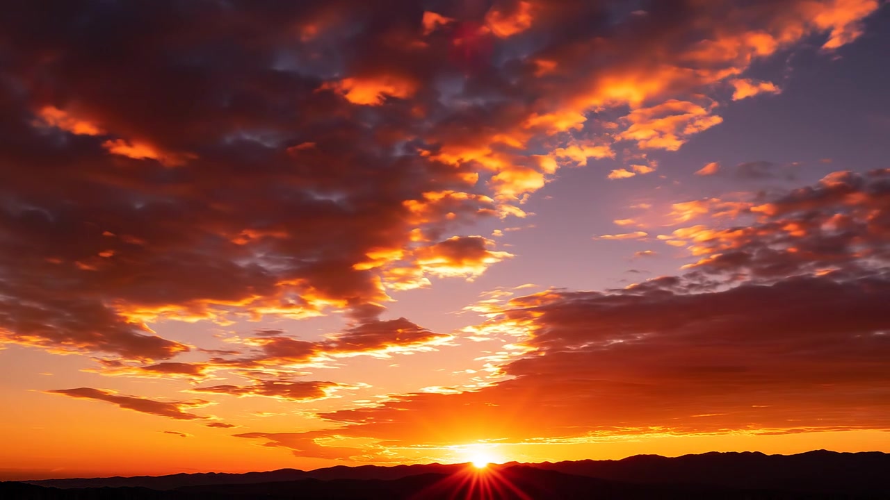 Farbenprächtiger Sonnenuntergang mit Sonnenstrahlen über einer Bergkette und dramatischem Wolkenhimmel