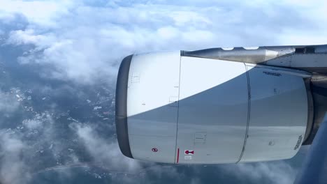 airplane engine against sky, fluffy clouds below, mid-flight perspective, sunny day