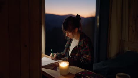 Woman Writing at Desk with Candlelight at Dusk