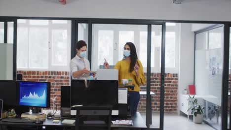 man and woman wearing face mask working together in office