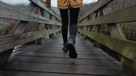 Slow-Motion-Young-lady-crossing-a-timber-footbridge-over-a-steam-in-countryside