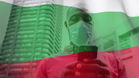 Bulgarian-flag-waving-against-man-wearing-face-mask-using-smartphone