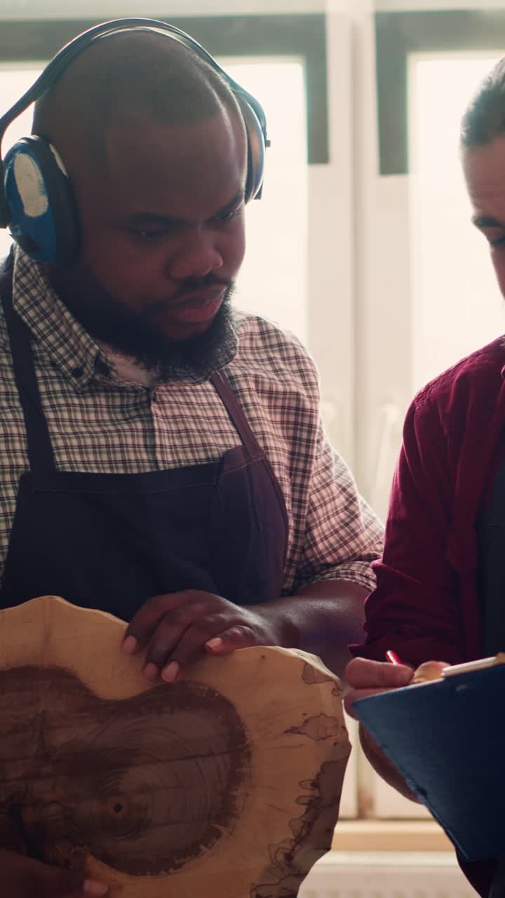 Two Woodworkers Discussing Project Details in Workshop