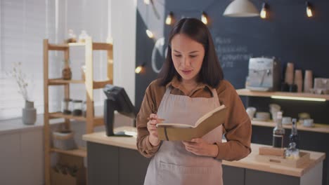 la cámara enfoca la cara de una camarera en una cafetería que toma notas en un cuaderno, mira a la cámara y sonríe 1